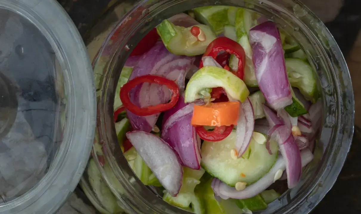 Słoik pełen świeżej sałatki z ogórków z chili, cebuli i papryki. Idealna na lato!