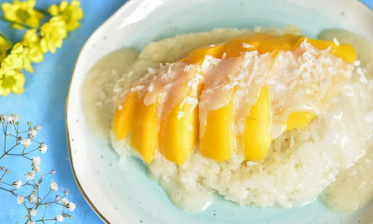 Słodki ryż z mleczkiem kokosowym i kawałkami mango, posypany wiórkami. Pyszny deser mango sticky rice.