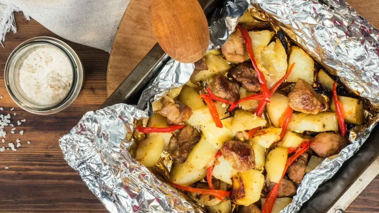 Pyszny obiad z piekarnika: pieczone ziemniaki z mięsem i papryczką chili, zawinięte w folię aluminiową.