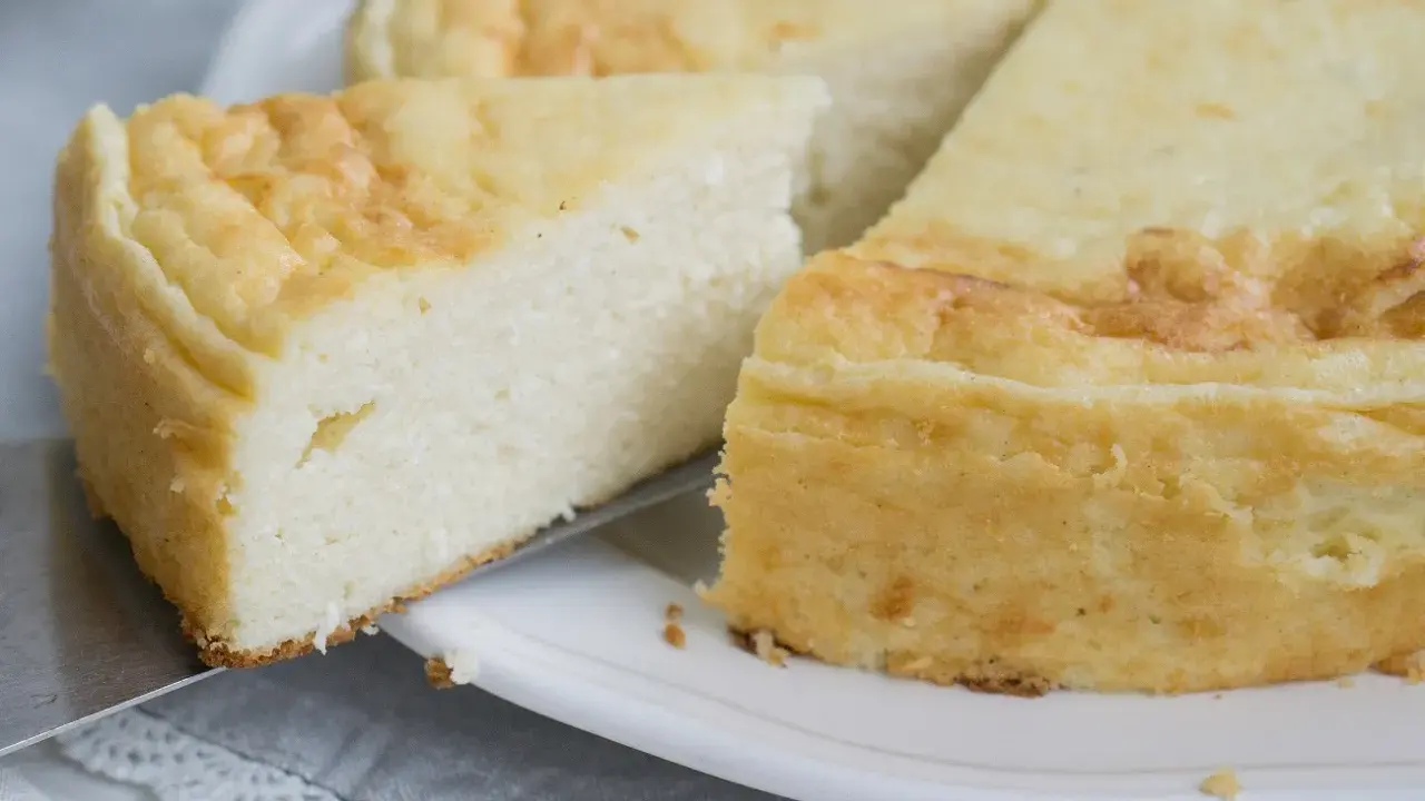 Puszysty sernik z mascarpone, z lekko zarumienioną skórką, kroimy na talerzu.