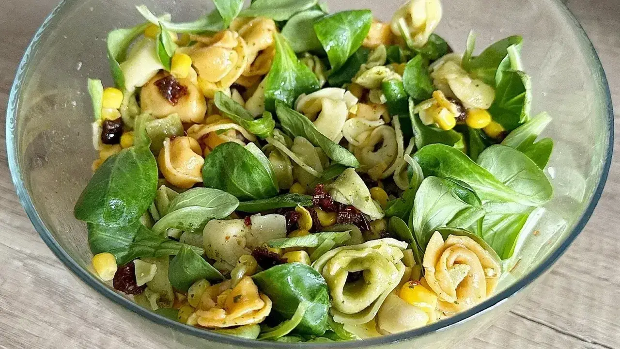 Kolorowa sałatka z tortellini, kukurydzą i suszonymi pomidorami w szklanej misce. Idealna na lekki posiłek.