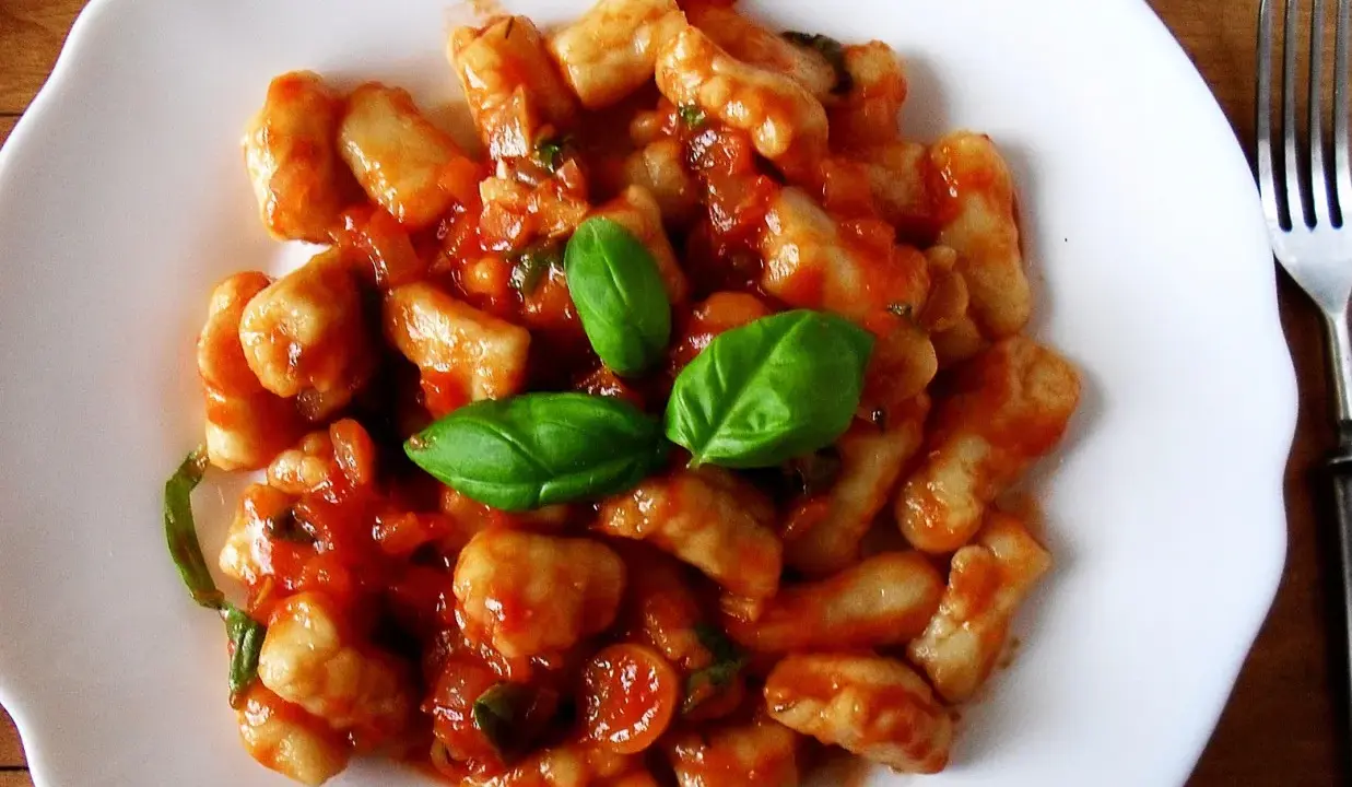 Pyszne gnocchi w sosie pomidorowym, udekorowane świeżą bazylią. Idealne danie na szybki obiad.