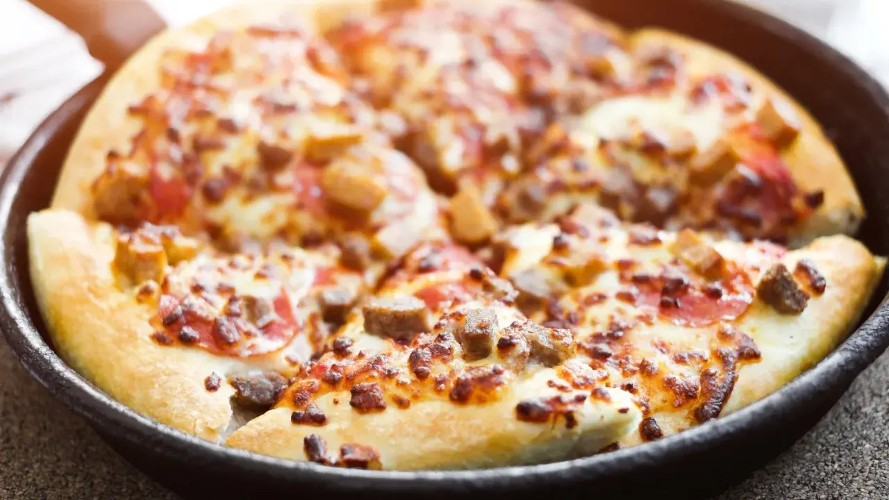 Pyszna pizza z patelni, z ciągnącym się serem i kawałkami mięsa, gotowa do podania.