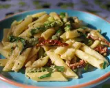 Penne z kremowym sosem, zielonymi szparagami i suszonymi pomidorami. Pyszny makaron ze szparagami na talerzu.