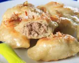 Złociste pierogi z mięsem z rosołu, okraszone skwarkami. Jeden pieróg przekrojony, ukazujący soczyste nadzienie.