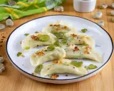 Pyszne pierogi z bobem, posypane skwarkami i koperkiem, prezentują się apetycznie na talerzu.