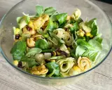 Kolorowa sałatka z tortellini, kukurydzą i suszonymi pomidorami w szklanej misce. Idealna na lekki posiłek.