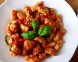 Pyszne gnocchi w sosie pomidorowym, udekorowane świeżą bazylią. Idealne danie na szybki obiad.