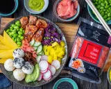 Kolorowy bowl z lososiem, edamame, mango, awokado, ogórkiem, rzodkiewką i ryżem. Obok opakowanie imbiru różowego.