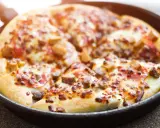 Pyszna pizza z patelni, z ciągnącym się serem i kawałkami mięsa, gotowa do podania.