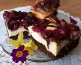 Pyszny sernik z wiśniami na czekoladowym spodzie, udekorowany kwiatami.