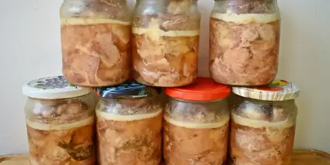 Siedem słoików z domowym mięsem w galarecie, gotowych do spiżarni.