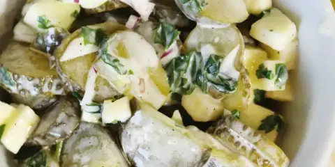 Pyszna sałatka z ogórków kiszonych, ziemniaków i cebuli, polana kremowym sosem. Idealna na letnie dni.