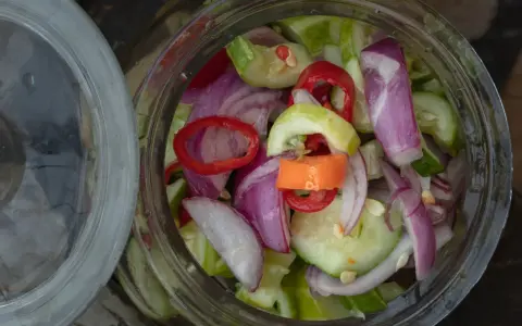 Słoik pełen świeżej sałatki z ogórków z chili, cebuli i papryki. Idealna na lato!