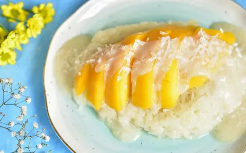 Słodki ryż z mleczkiem kokosowym i kawałkami mango, posypany wiórkami. Pyszny deser mango sticky rice.