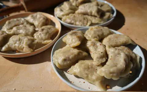 Trzy talerze pełne pysznych, domowych pierogów z soczewicą, posypanych przyprawami.