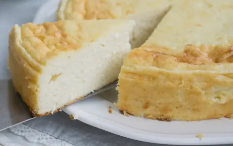 Puszysty sernik z mascarpone, z lekko zarumienioną skórką, kroimy na talerzu.