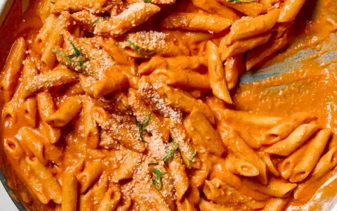 Penne alla vodka w kremowym, pomarańczowym sosie, posypane parmezanem i bazylią. Idealne danie na szybki obiad.