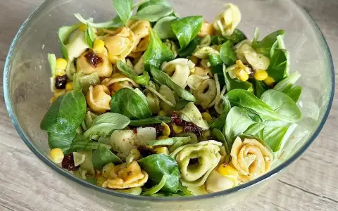 Kolorowa sałatka z tortellini, kukurydzą i suszonymi pomidorami w szklanej misce. Idealna na lekki posiłek.