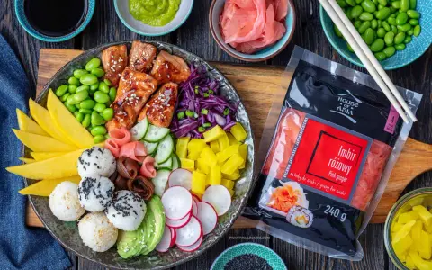 Kolorowy bowl z lososiem, edamame, mango, awokado, ogórkiem, rzodkiewką i ryżem. Obok opakowanie imbiru różowego.