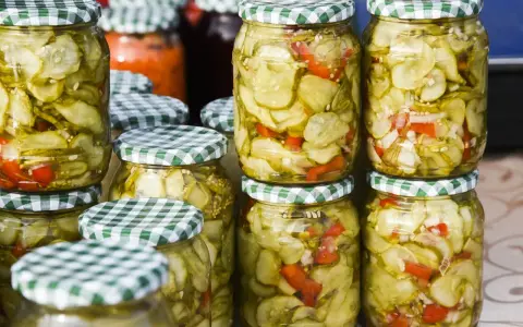 Słoiki z sałatką z ogórków w zalewie gyros, z dodatkiem papryki i cebuli, gotowe do spiżarni.