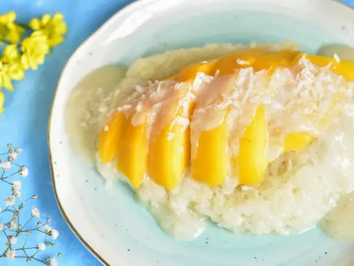 Słodki ryż z mleczkiem kokosowym i kawałkami mango, posypany wiórkami. Pyszny deser mango sticky rice.