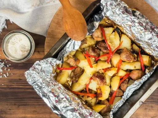 Pyszny obiad z piekarnika: pieczone ziemniaki z mięsem i papryczką chili, zawinięte w folię aluminiową.