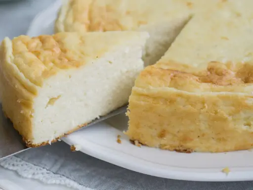 Puszysty sernik z mascarpone, z lekko zarumienioną skórką, kroimy na talerzu.