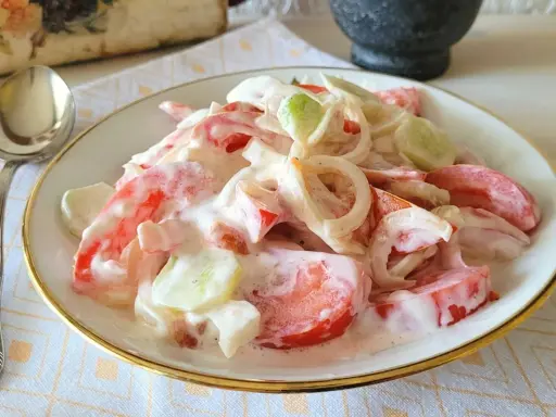 Pyszna sałatka z pomidora, ogórka i cebuli w kremowym sosie. Idealna na letni obiad.