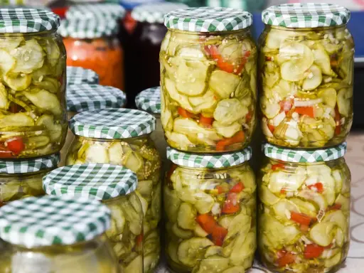 Słoiki z sałatką z ogórków w zalewie gyros, z dodatkiem papryki i cebuli, gotowe do spiżarni.