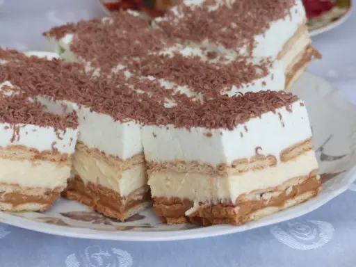 Pyszne, tanie ciasto bez pieczenia z herbatnikami, kremem i karmelem, posypane wiórkami czekoladowymi. Idealne na deser!