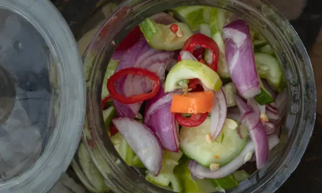 Słoik pełen świeżej sałatki z ogórków z chili, cebuli i papryki. Idealna na lato!