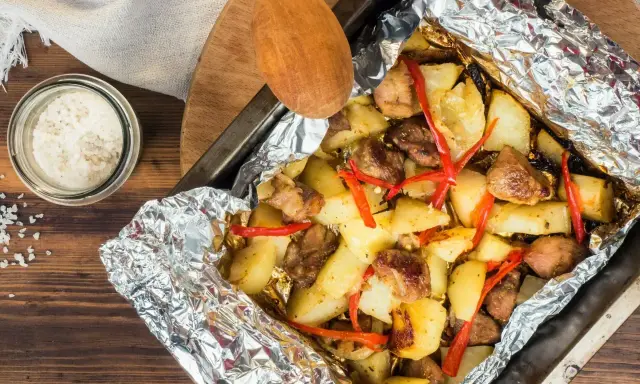 Pyszny obiad z piekarnika: pieczone ziemniaki z mięsem i papryczką chili, zawinięte w folię aluminiową.