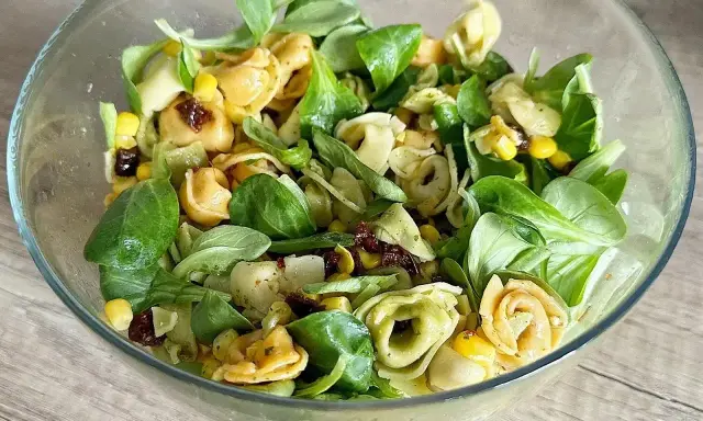 Kolorowa sałatka z tortellini, kukurydzą i suszonymi pomidorami w szklanej misce. Idealna na lekki posiłek.