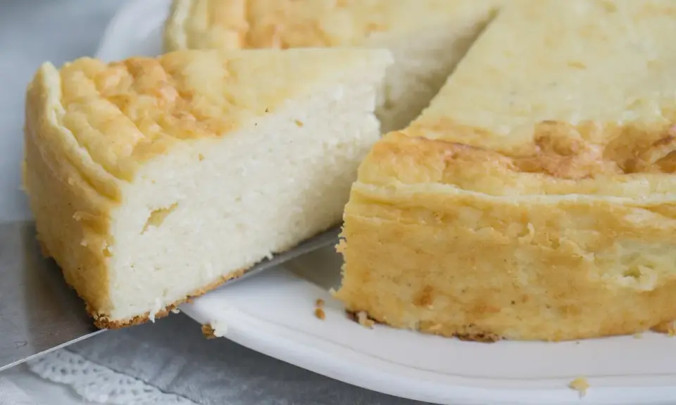 Puszysty sernik z mascarpone, z lekko zarumienioną skórką, kroimy na talerzu.