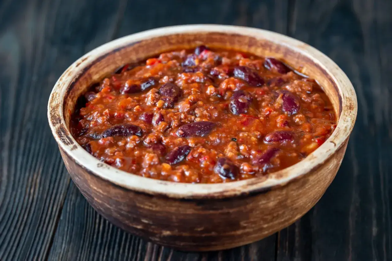 Gęste, aromatyczne chili con carne z fasolą i mielonym mięsem w glinianej misce, gotowe do podania.