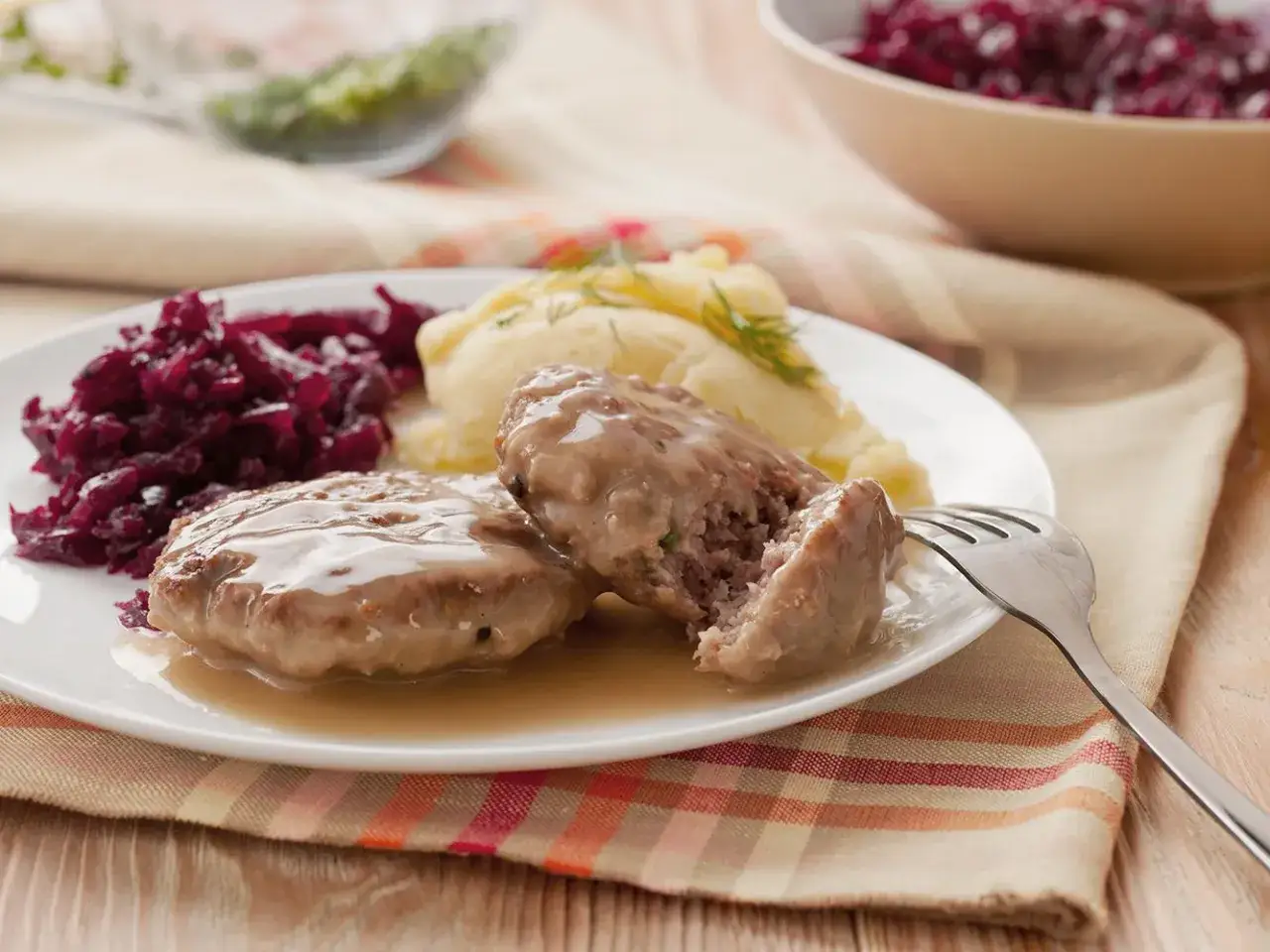 Dwa soczyste zrazy z mięsa mielonego w sosie, podane z purée ziemniaczanym i czerwoną kapustą. Pyszny obiad!
