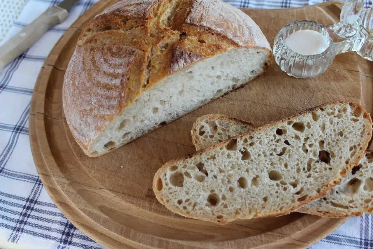 Chleb na zakwasie, pokrojony na desce, z solniczką i nożem. Idealny na śniadanie.