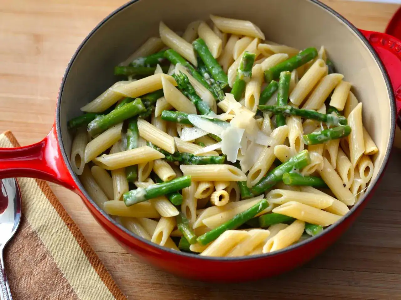 Penne z zielonymi szparagami i parmezanem w czerwonym naczyniu. Pyszny makaron ze szparagami.
