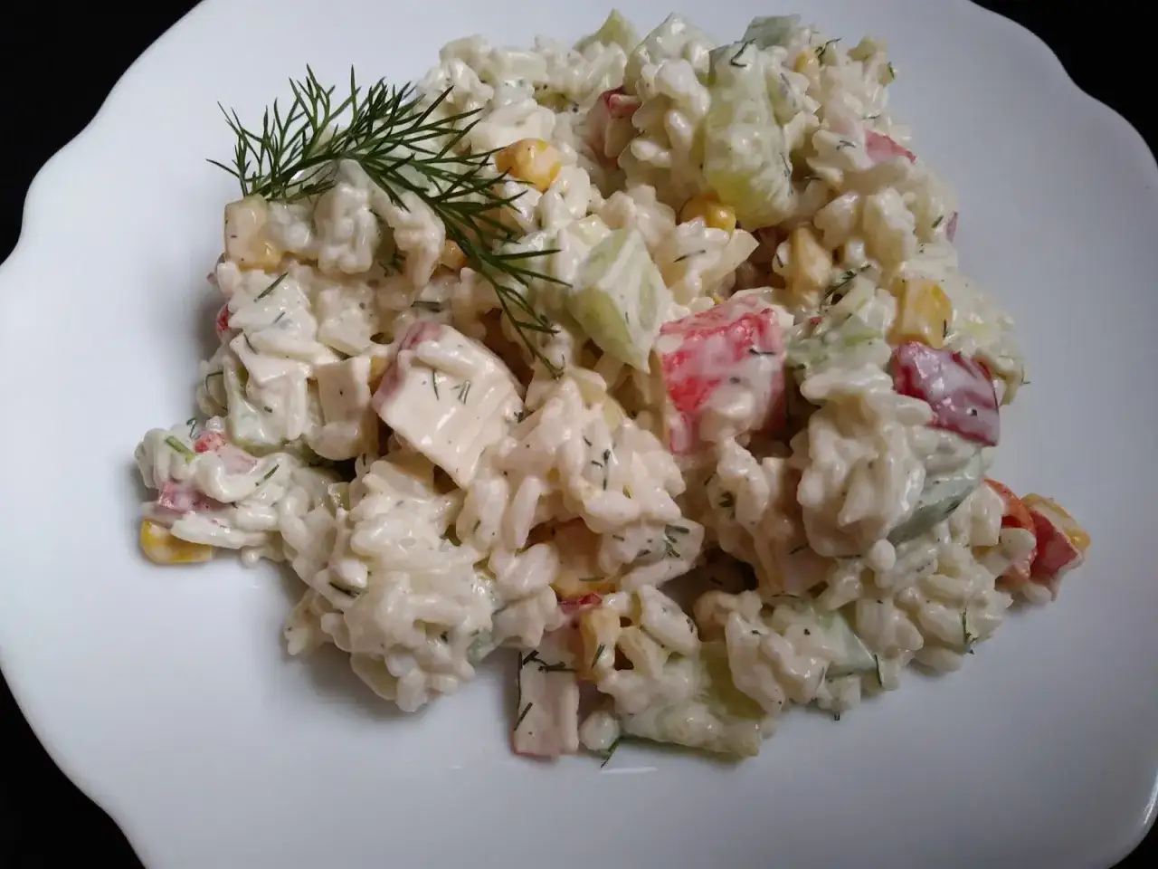 Pyszna sałatka z surimi, ryżu, kukurydzy i ogórka, doprawiona koperkiem.