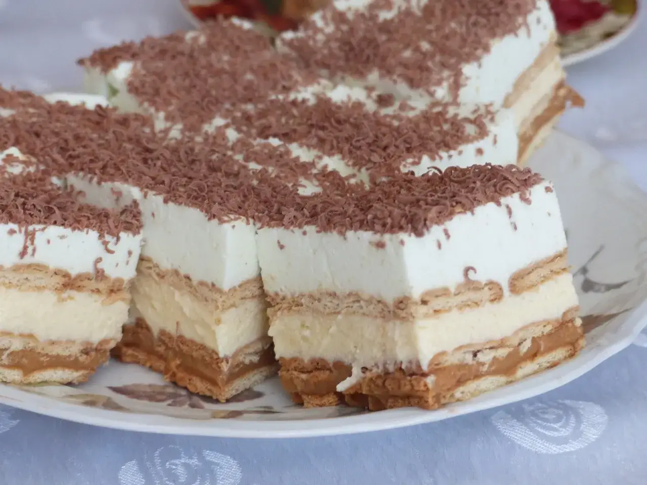 Pyszne, tanie ciasto bez pieczenia z herbatnikami, kremem i karmelem, posypane wiórkami czekoladowymi. Idealne na deser!
