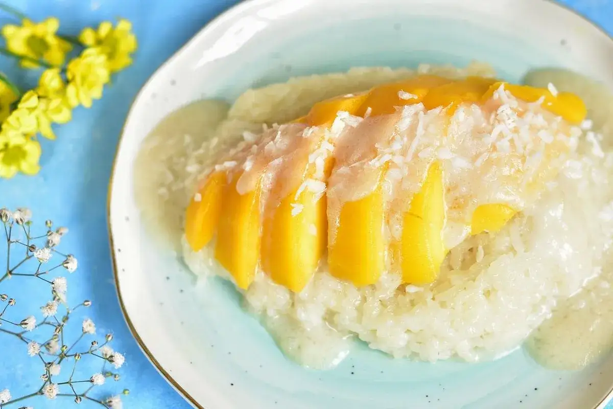 Słodki ryż z mlekiem kokosowym i kawałkami mango, posypany wiórkami. Pyszny deser mango sticky rice.