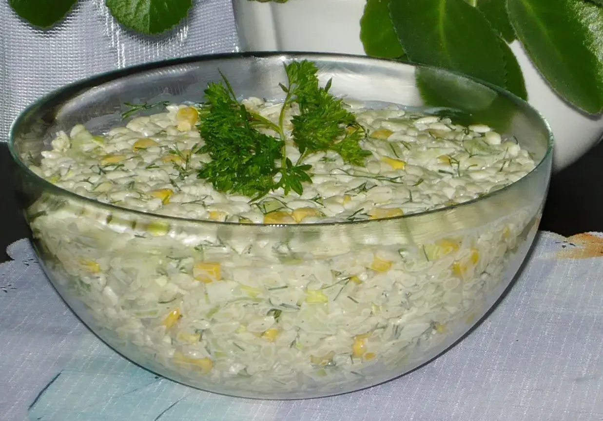 Pyszna sałatka na grilla z makaronem, kukurydzą i ziołami, podana w szklanej misie.