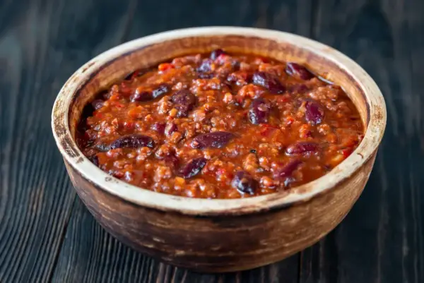 Gęste, aromatyczne chili con carne z fasolą i mielonym mięsem w glinianej misce, gotowe do podania.