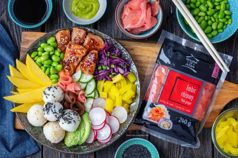 Kolorowy bowl z lososiem, edamame, mango, awokado, ogórkiem, rzodkiewką i ryżem. Obok opakowanie imbiru różowego.